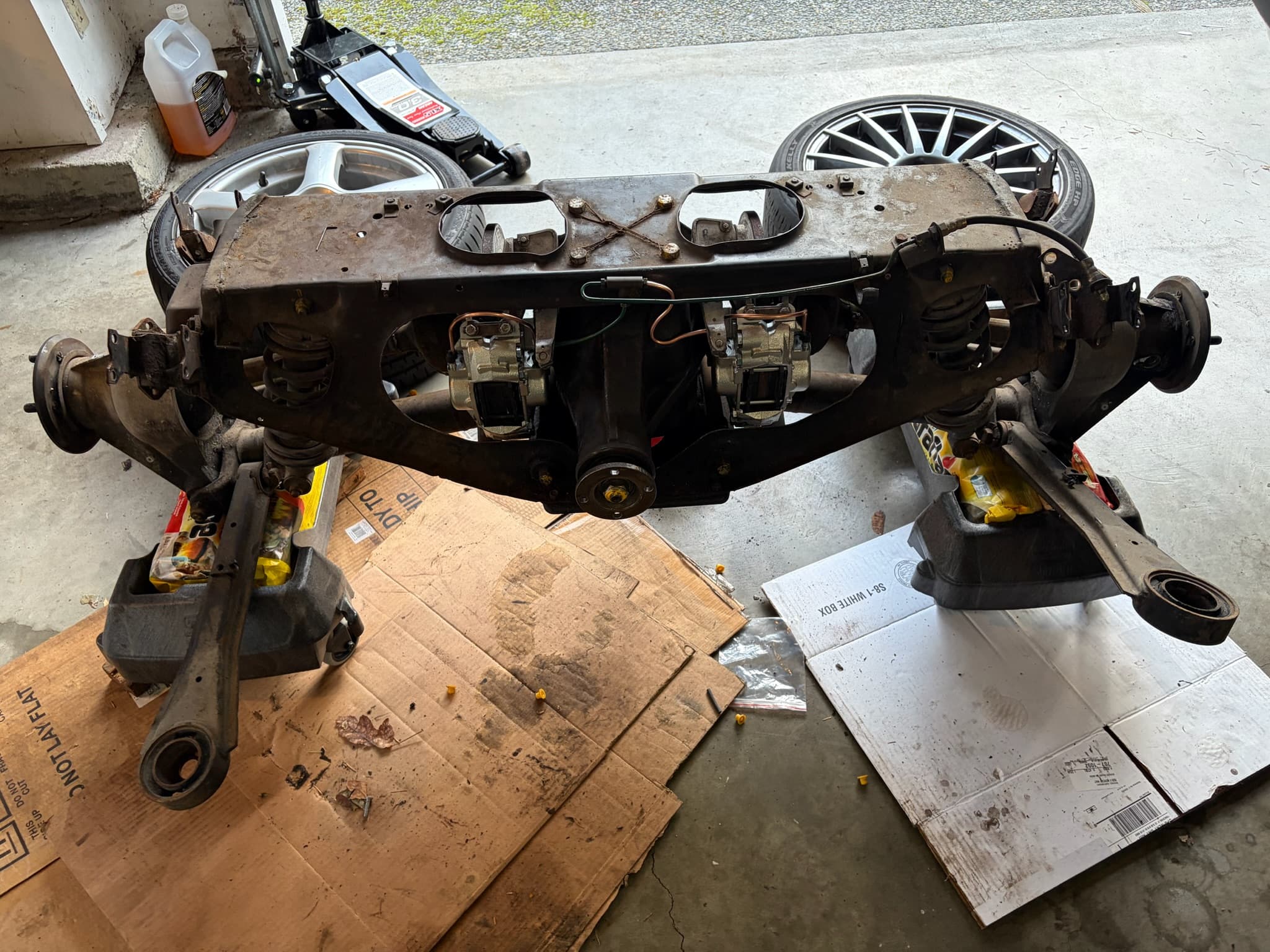 Full view of the rear subframe on the garage floor with new calipers fitted